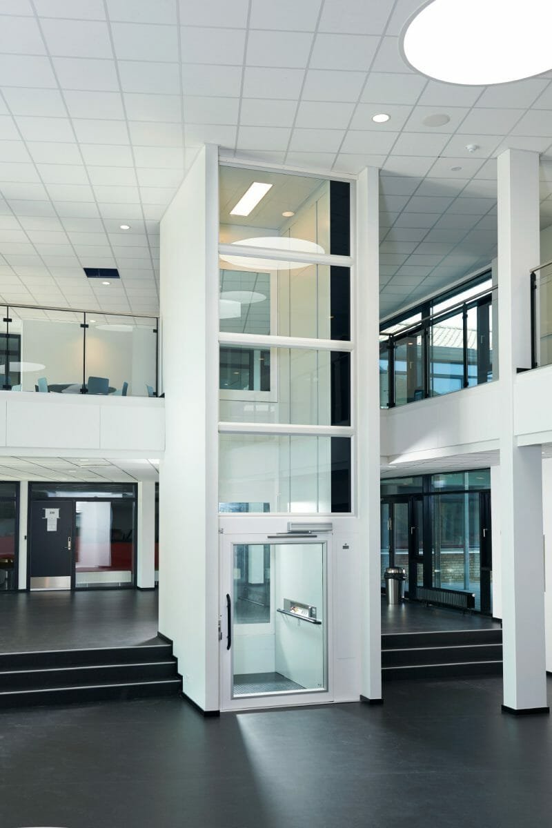 Platformlift met glazen schacht in een kantooratrium