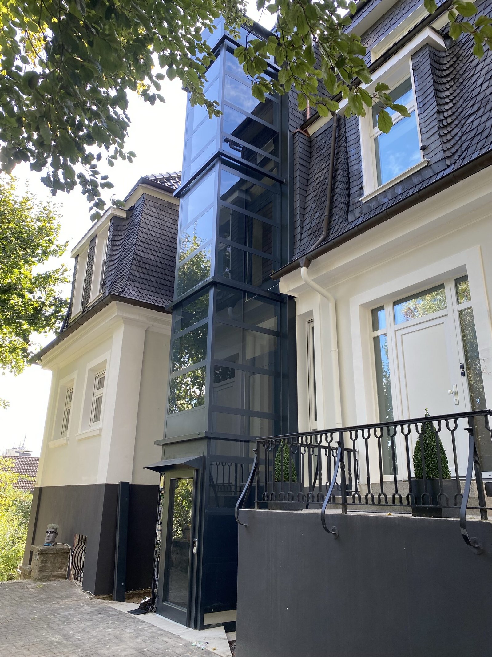 Design huislift met donkere schacht langs een woning