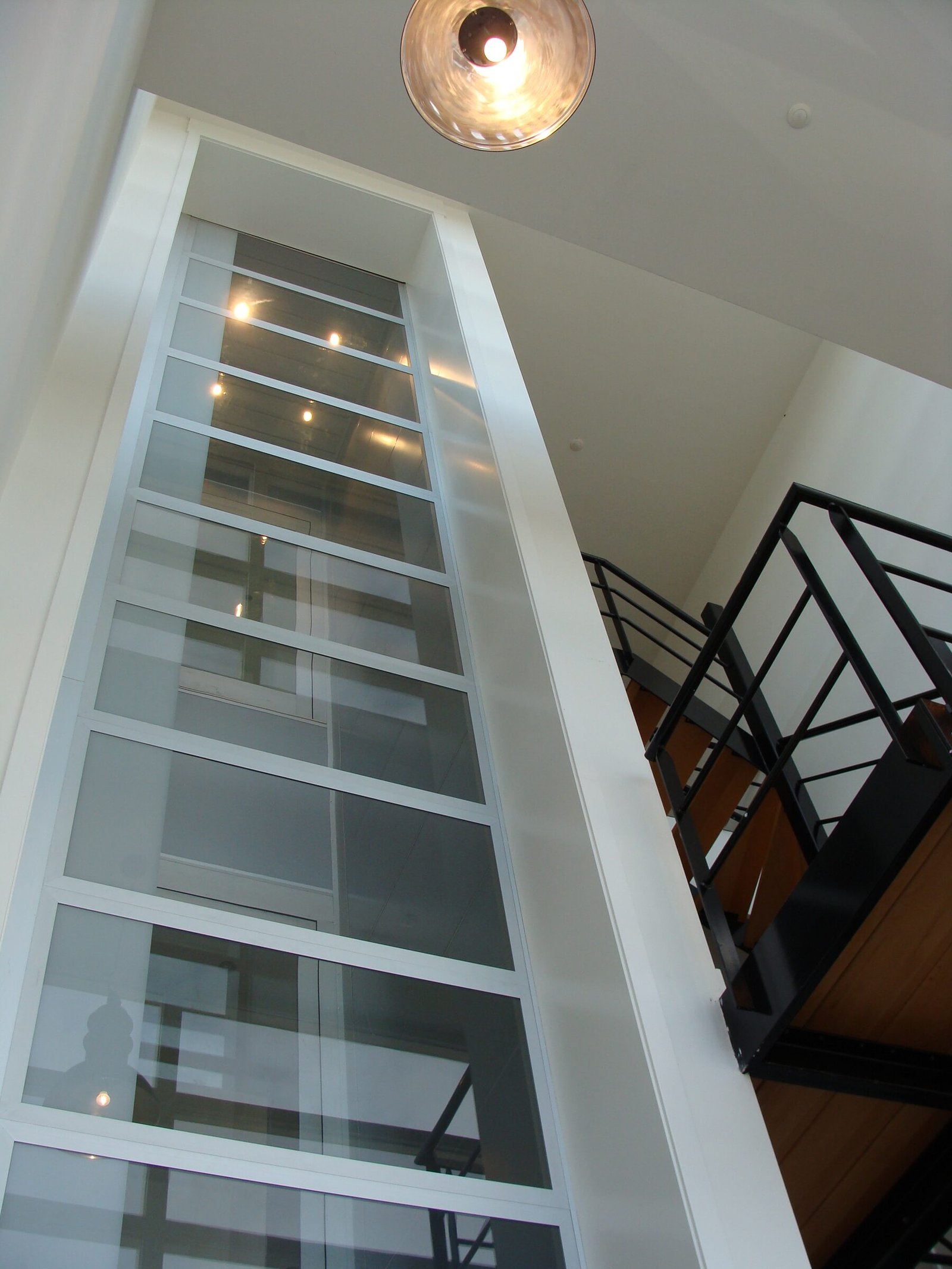 Hoge glazen schacht van de design huislift in een trappenhuis
